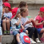 Een schoolklasje onder begeleiding van ouders dat de lunch verorbert.